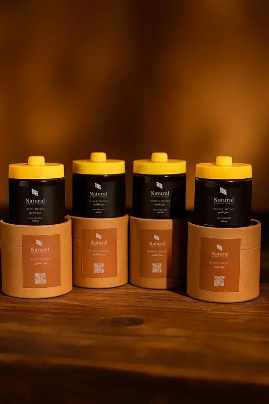 Four jars of Natural Organic Honey with yellow lids and brown packaging on wooden surface