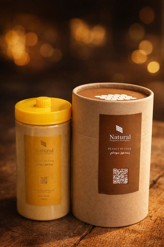 Natural Organic Delights peanut butter in a yellow jar and brown paper tube on wooden table