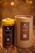 Natural organic Royal Athel honey in clear bottle with yellow lid and brown packaging on wood