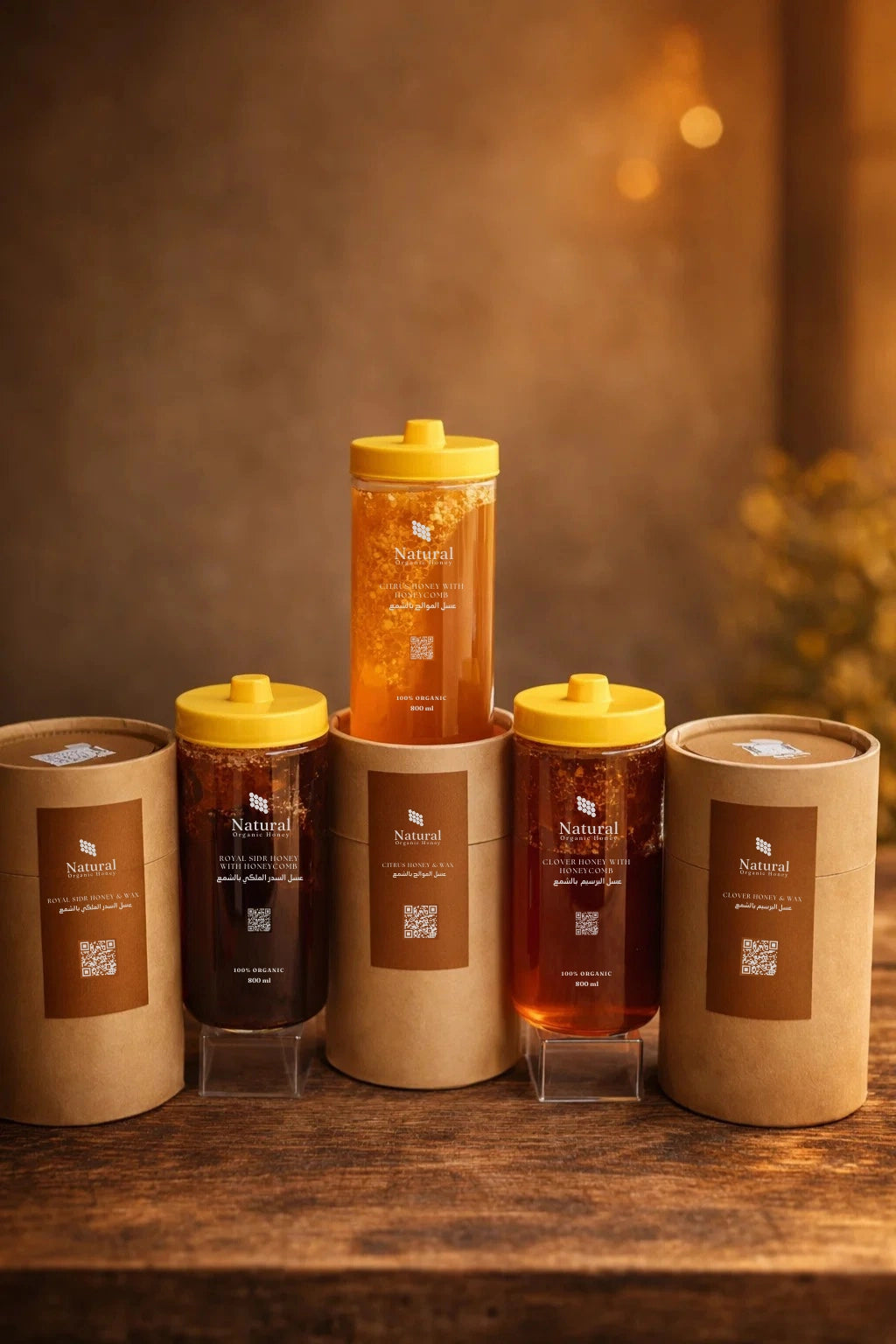 Triple honeycomb package with natural organic honey jars and brown cylindrical boxes on wooden table